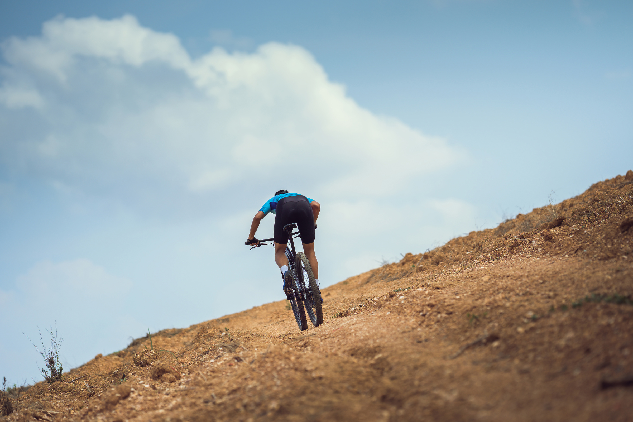 Mountain biker cycling, training and going up a steep climb.